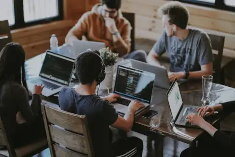 A services team working on laptops around a shared table