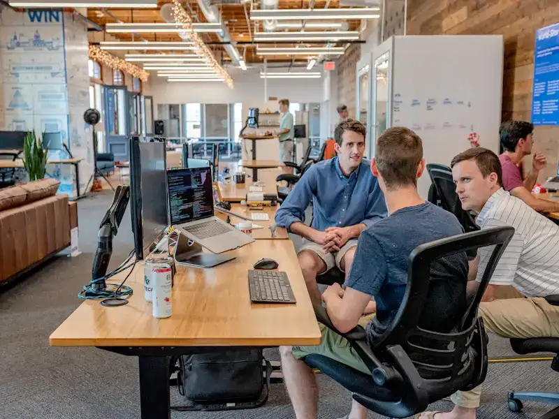 A team meeting around a desk in an open-plan office