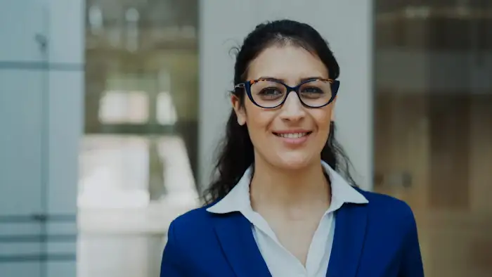 A smiling professional in glasses and a blue blazer